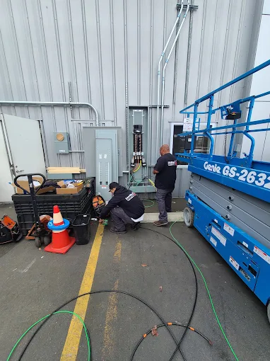 Live Wire Electric technicians working beside electrical panels and a lift in a commercial building