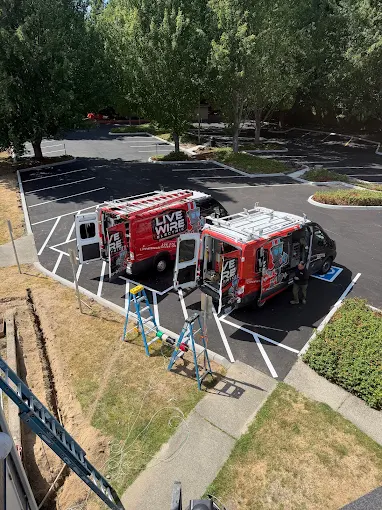 Two Live Wire Electric vans and ladders at a job site