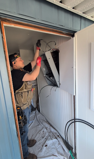 A technician removing an electrical panel enclosure from a wall