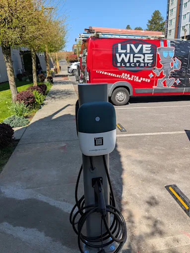 An electric vehicle charger with a Live Wire Electric service van behind it