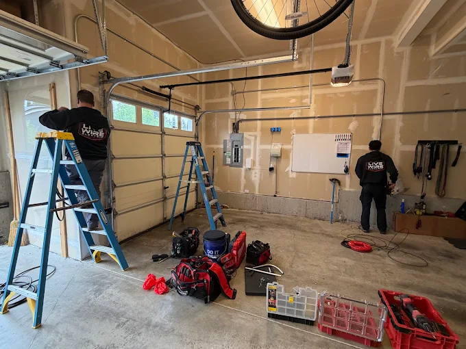 Two Live Wire Electric technicians installing electrical wiring in a garage