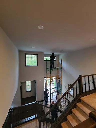 A technician on scaffolding in a tall entryway with a staircase