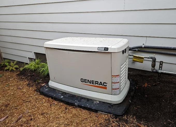 A Generac standby generator on a pad beside a house